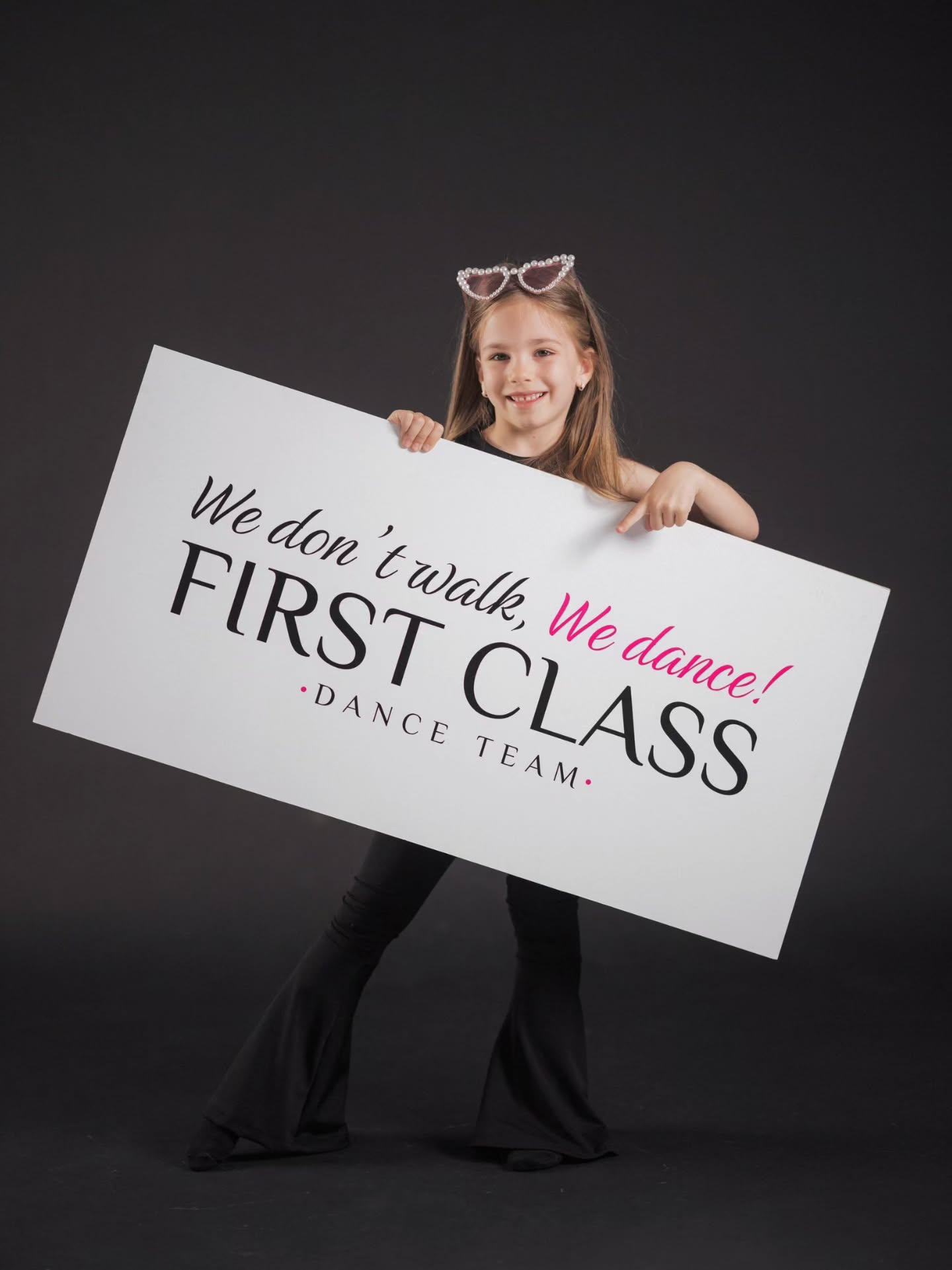 Mala plesačica drži tablu sa sloganom First Class Dance Team